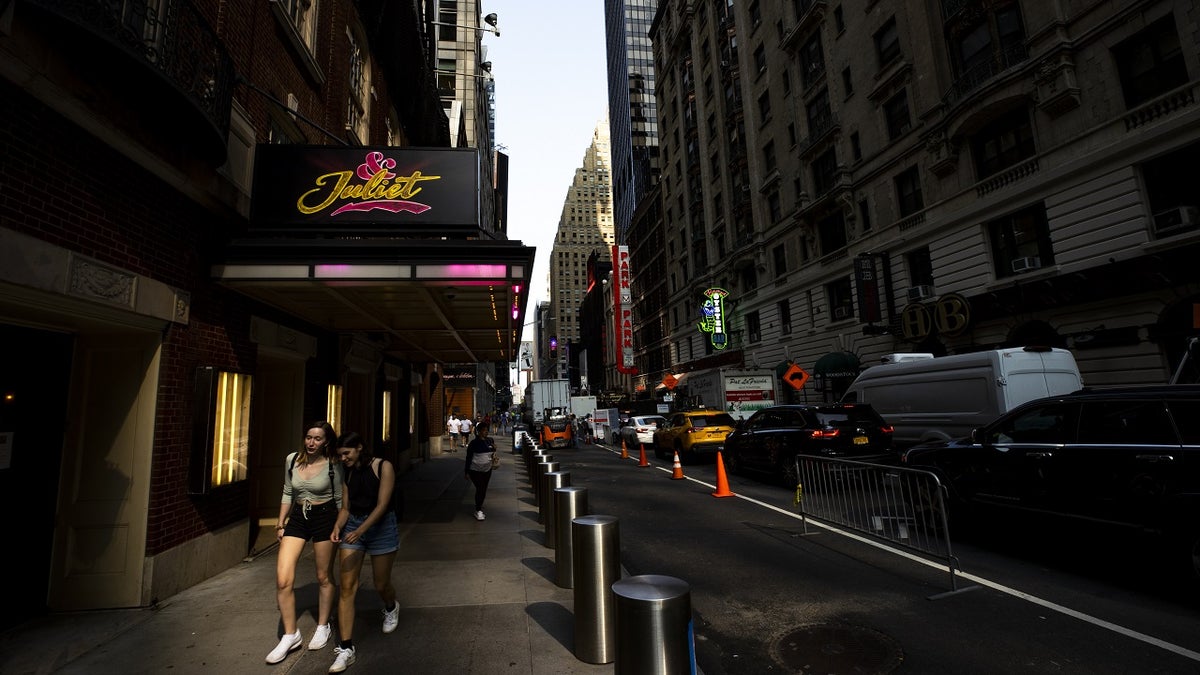 Two women standing near a broadway theater
