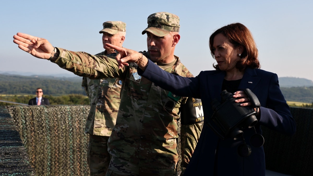 Harris pointing outward with two U.S. service members
