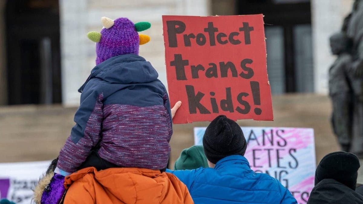 protester holds pro-trans sign