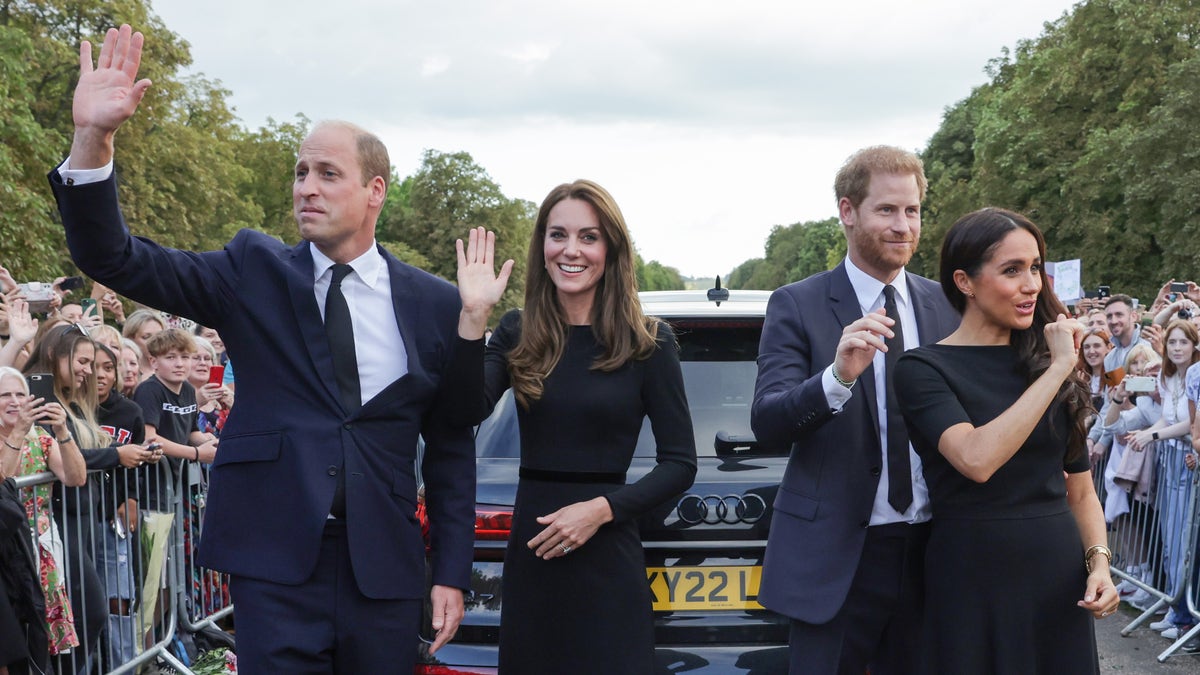 Princes and their wives wave to gatherers outside Windsor Castle