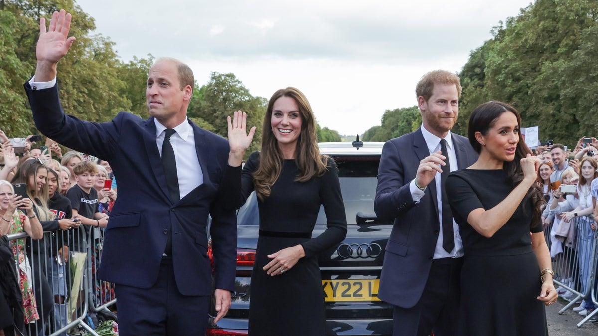 Princes and their wives wave to gatherers outside Windsor Castle