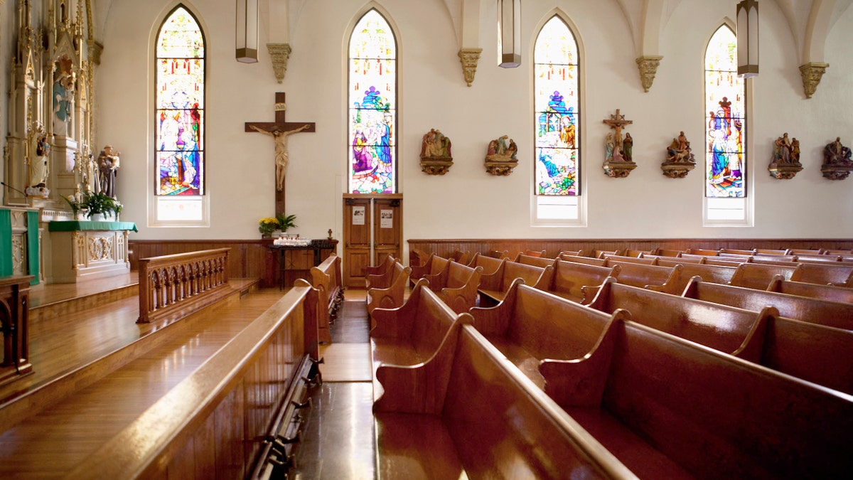 A church with stained glass windows stands empty church pews