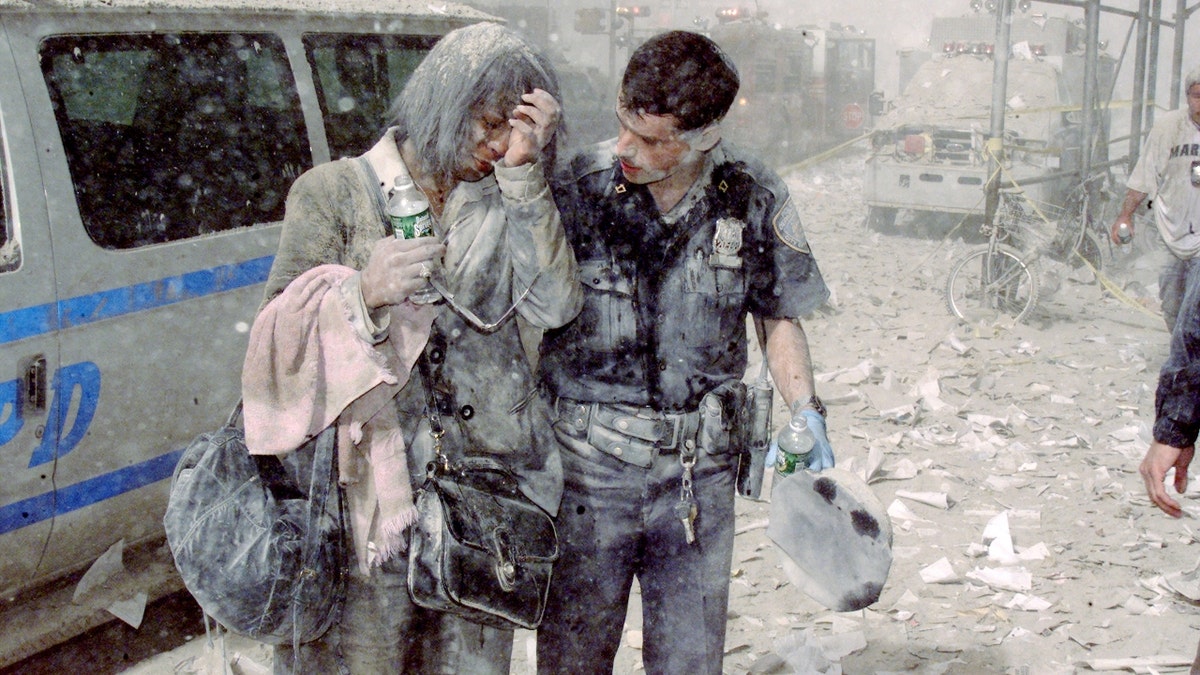 A police officer and woman covered in dust walk through wreckage after 9/11 in New York City