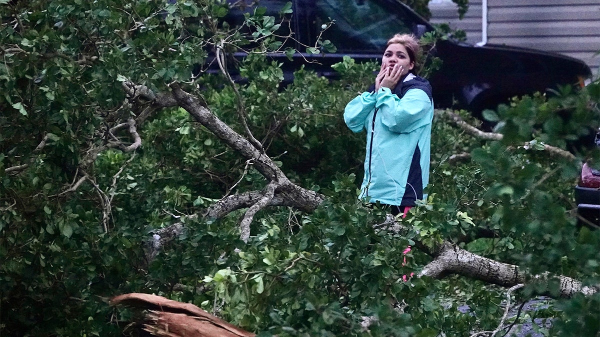 A woman covers her mouth in shock as hurricane Ian damages mobile home in Florida