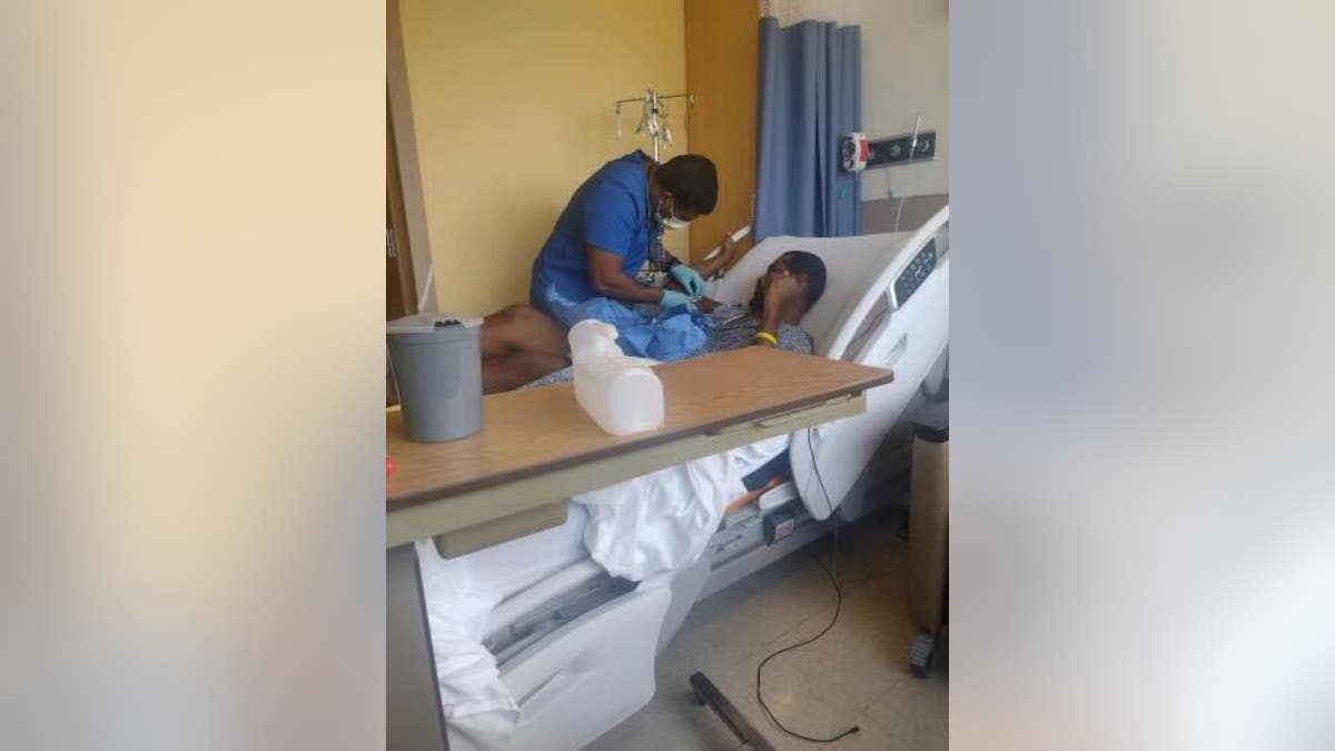 Raheem Bell in a hospital bed as medical staff treats him