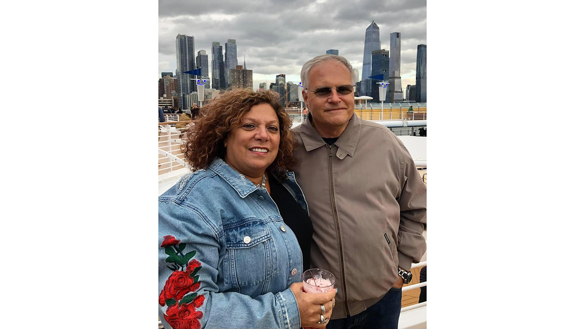 Michael and Denise Verzi in jackets with an overcast New York City skyline behind them