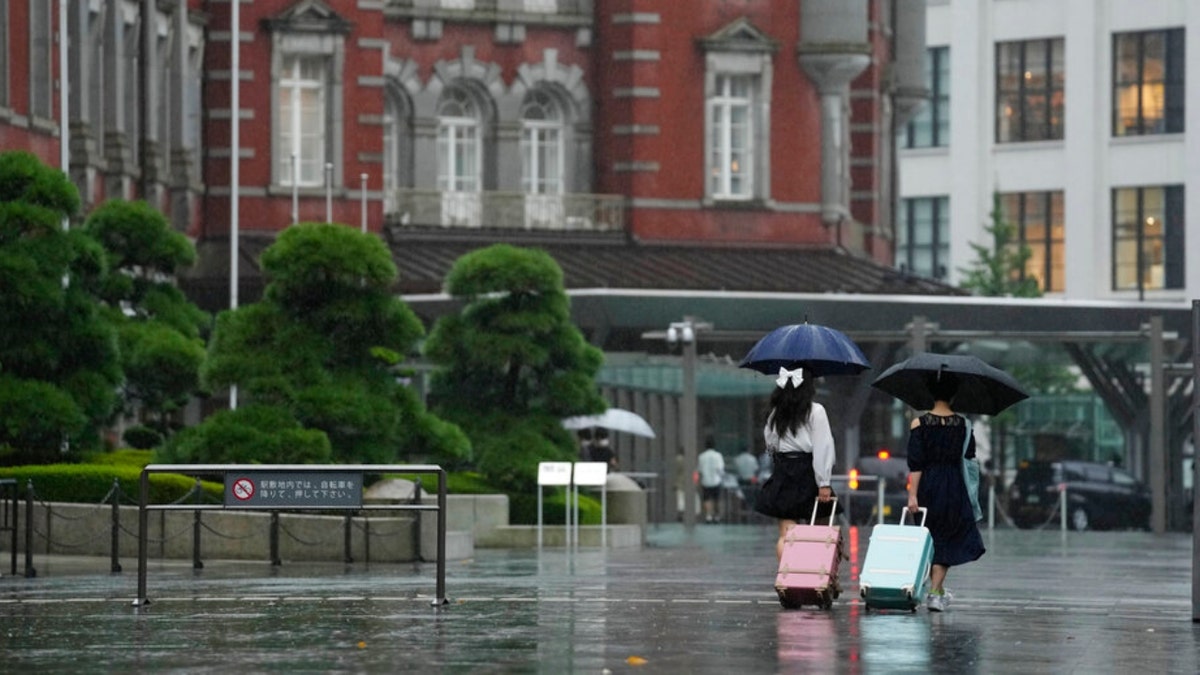 Women with umbrellas walk out in the rain