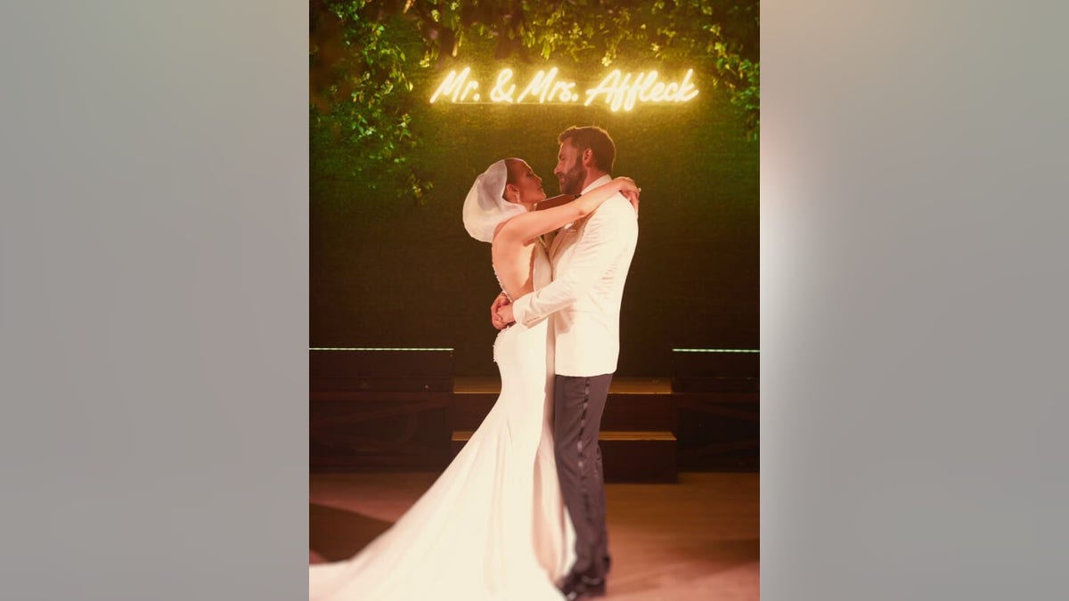 Jennifer Lopez stands underneath a sign with husband Ben Affleck