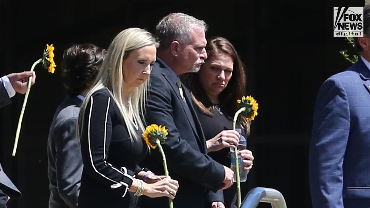 Allison "Allie" Rice's father, Paul Rice, and other Angela Engler, clutch sunflowers at her funeral