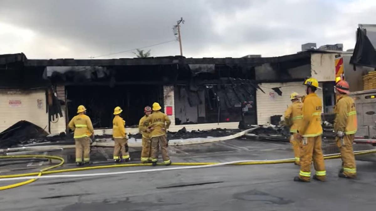 Firefighters stand outside of burned strip mall