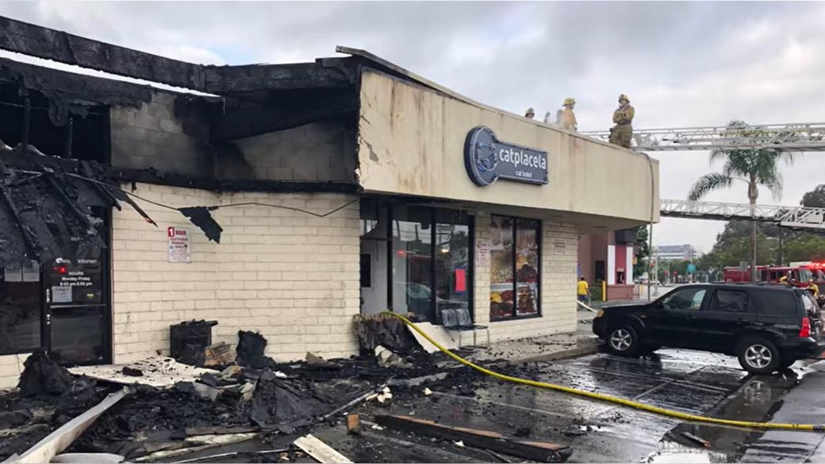 Firefighters standing on top of a burned strip mall 