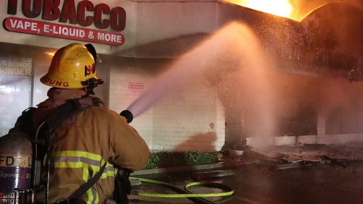 Firefighter puts water on fire at strip mall