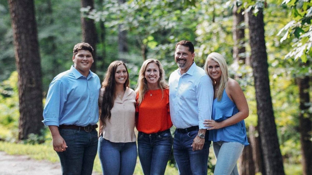 A couple poses for a picture outside with their three children