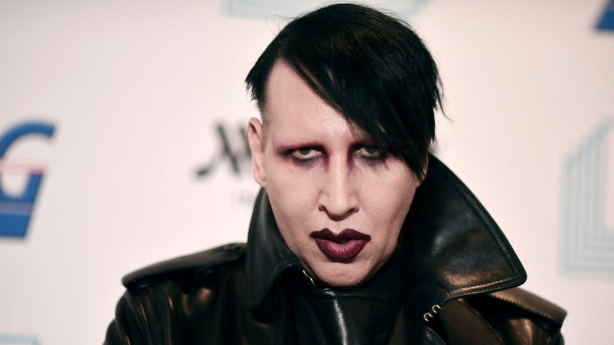 Marilyn Manson walks red carpet wearing black leather jacket and lipstick