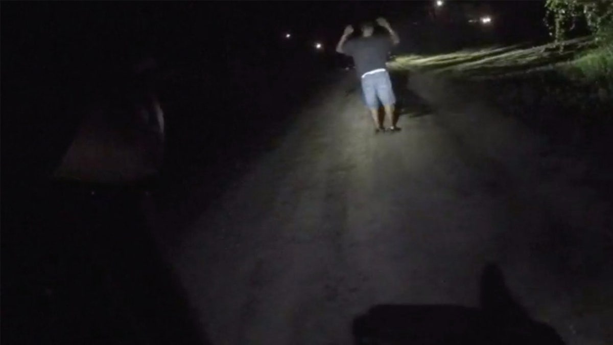Michael Williams stands on a road with his hands up.