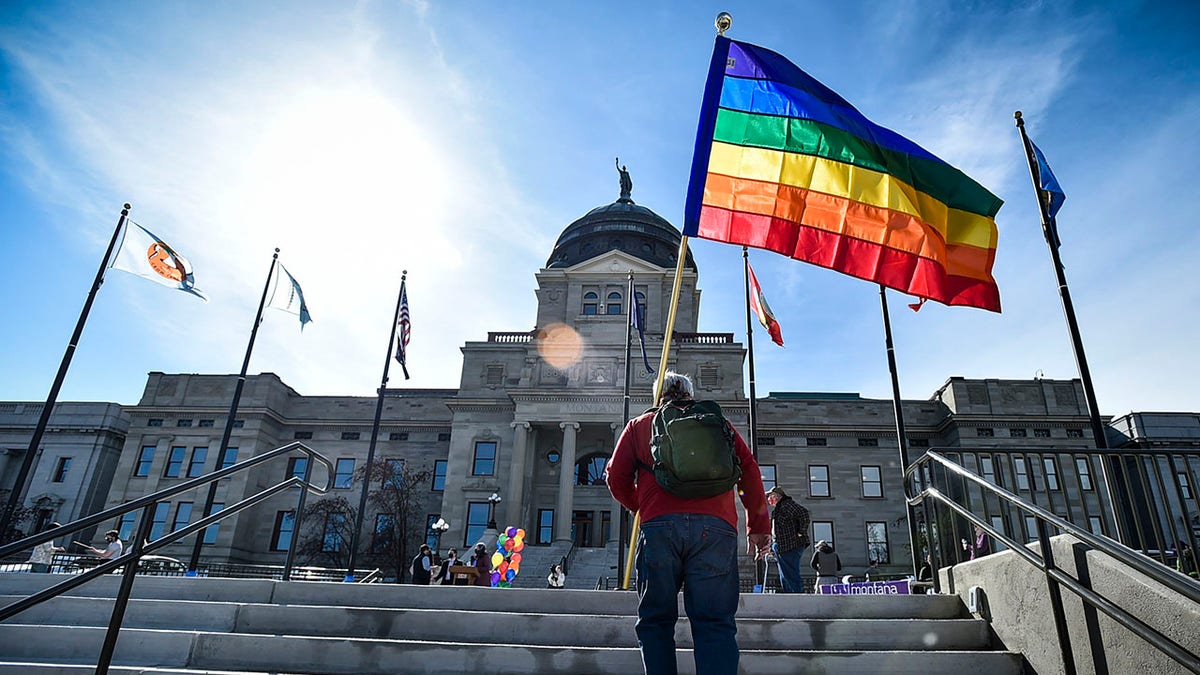 man carries rainbow emblem up stairs extracurricular Kansas authorities capitol
