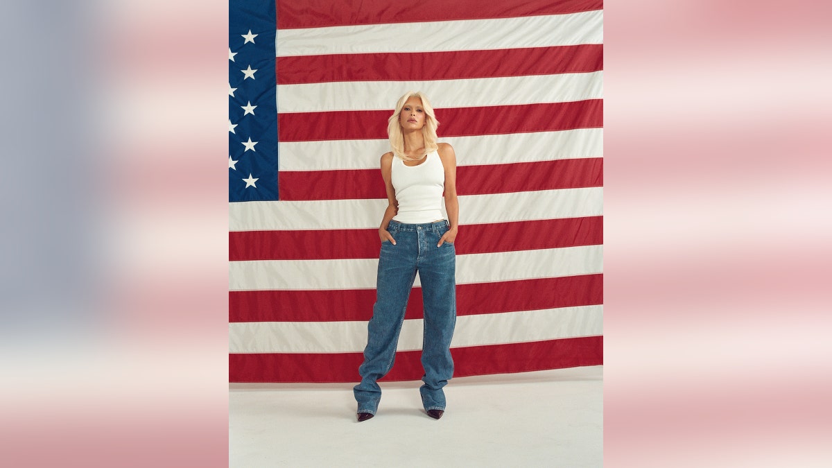 Kim Kardashian poses in front of an American Flag