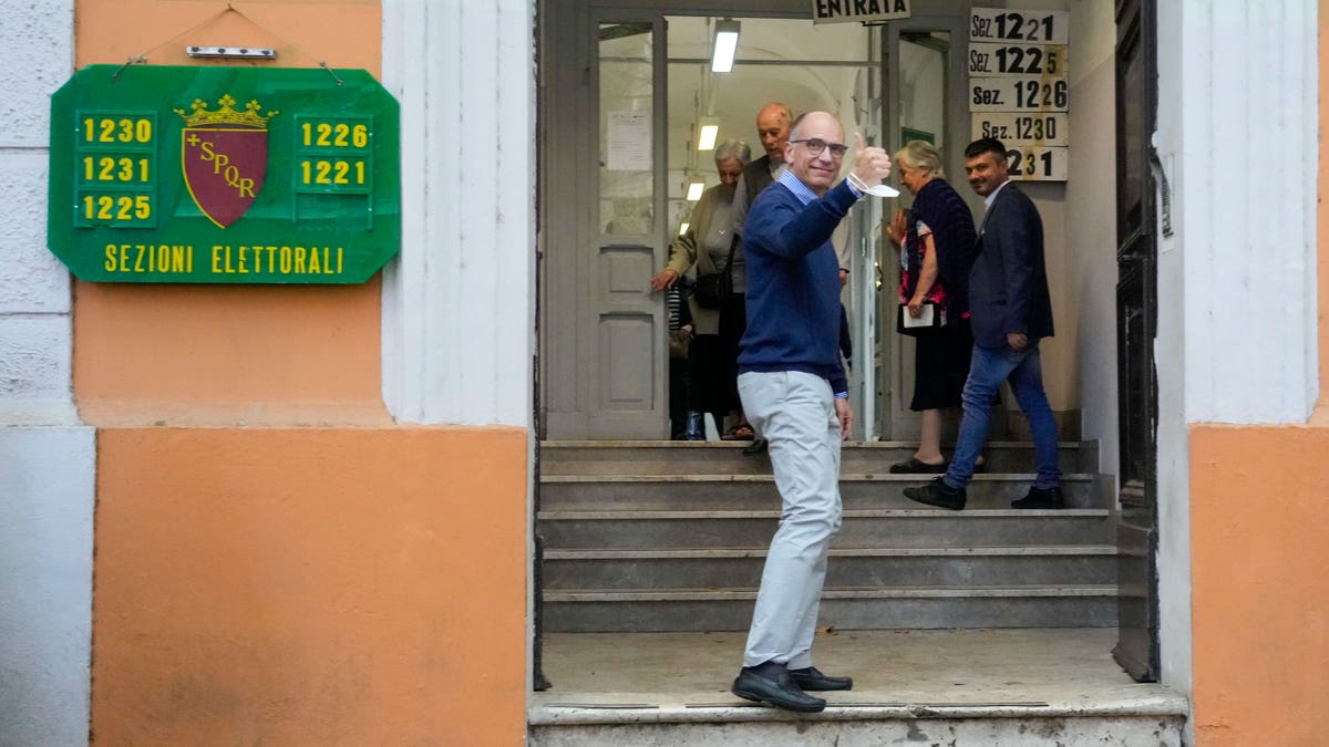Enrico Letta entering a polling station giving a thumbs up while walking up steps