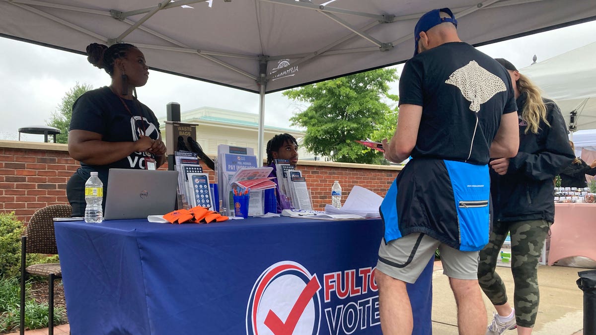 Man standing at poll worker sign up booth