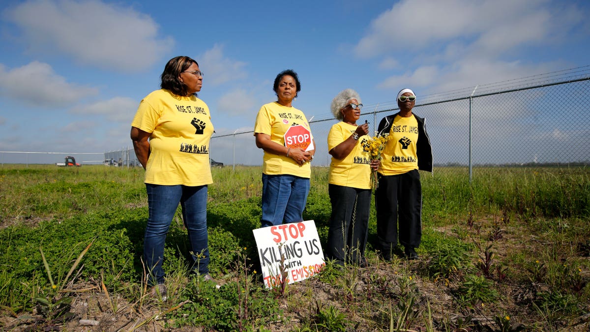 Protesters wearing yellow shirts standing in front of a chain link fence