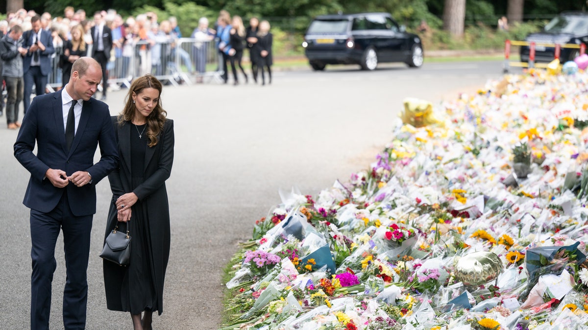 Prince William and Kate Middleton look at floral tributes