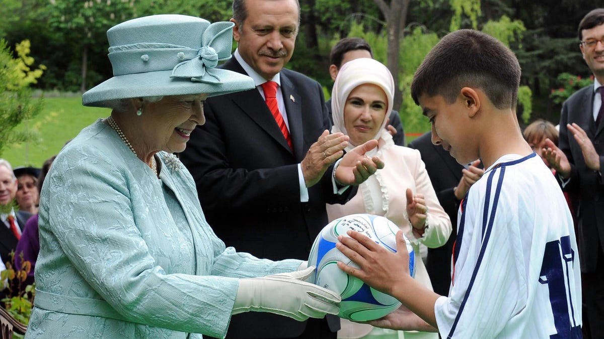 Queen Elizabeth II hands over soccer ball