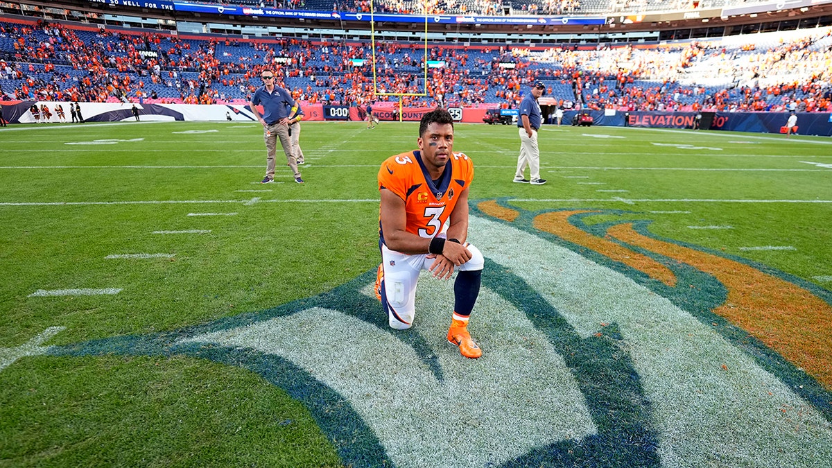 Russell Wilson kneels at mid field