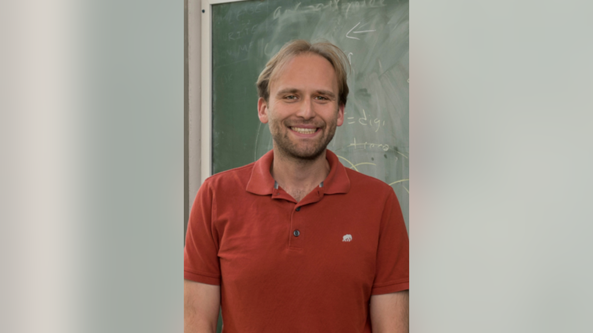 NIU physics professor Jahred Adelman seen smiling in his official school headshot
