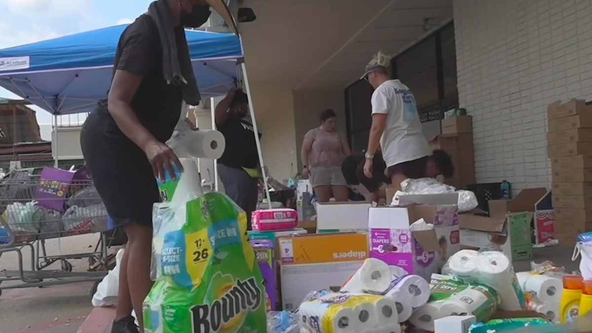 Woman with cowboy hat picks up pack of paper towels at supply giveaway