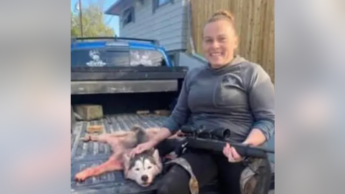 Amanda Rose Barnes smiles broadly as she poses with a skinned Siberian Husky
