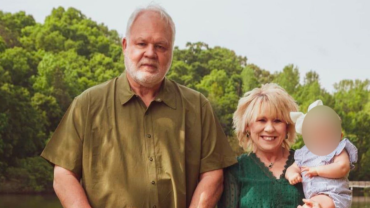 Steven and Debbie Collier pose together smiling in front of trees