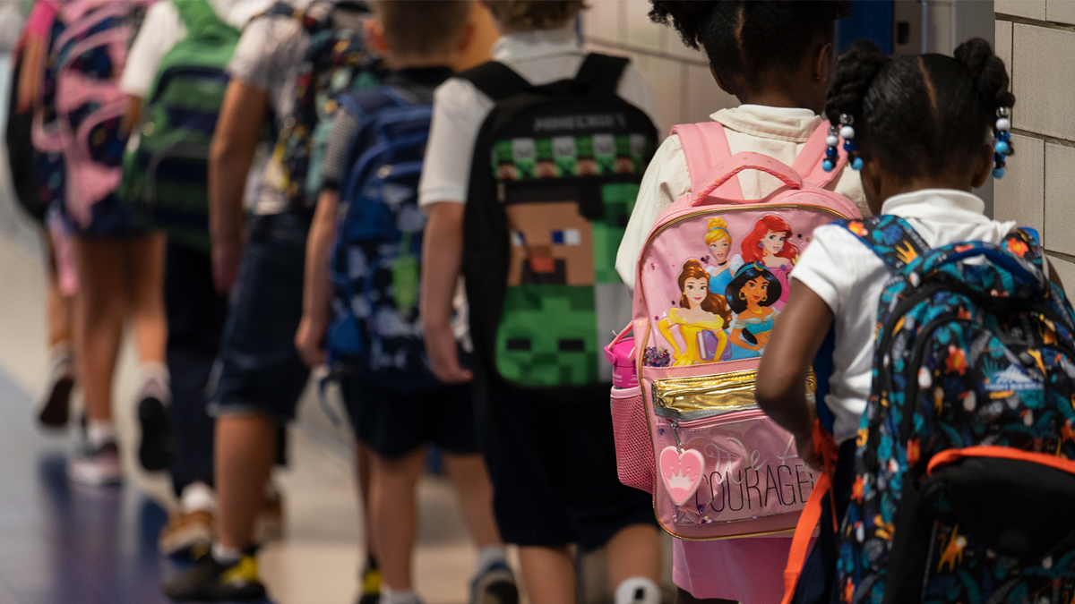 children wearing backpacks in line in school building