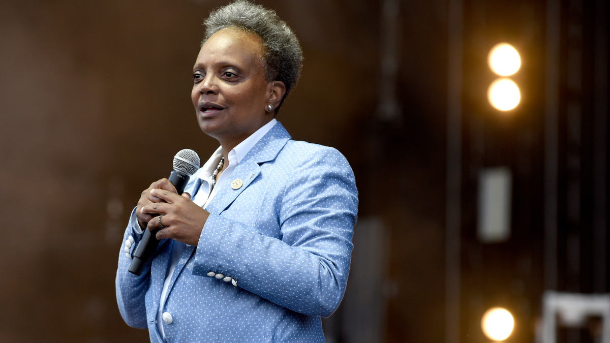 Lori Lightfoot seen holding a mic and speaking on stage in July of 2022