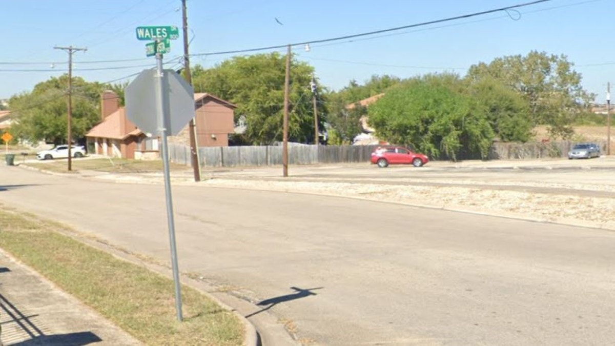 Two streets meet at a corner with a red car in the background