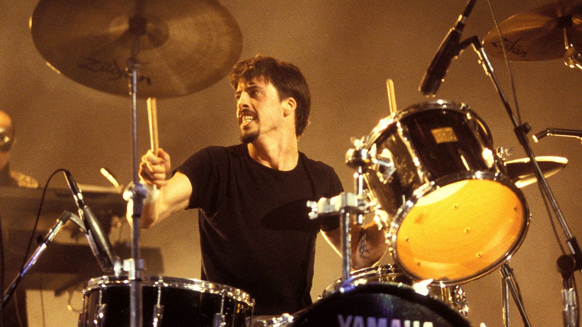 David Grohl playing the drums on stage looking to his right