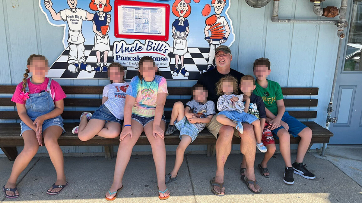 Photo shows Mark Houck on bench surrounded by his kids