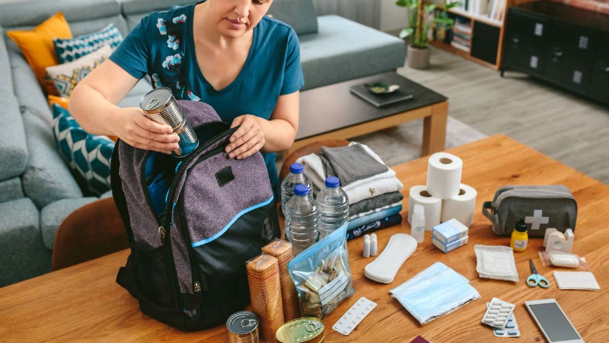 Woman packs emergency supplies in backpack