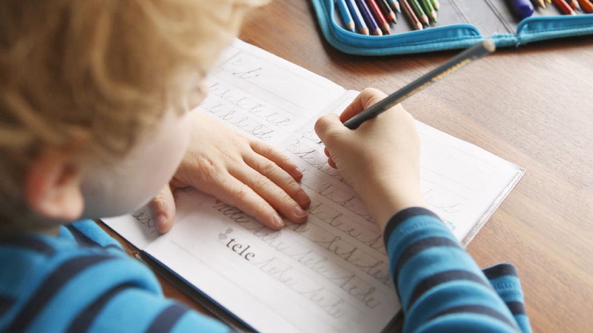 boy writes letters in script