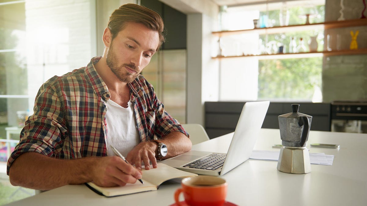 man writes in journal