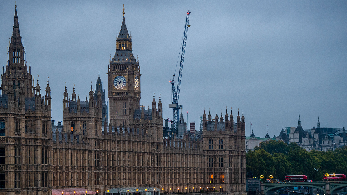 The photo shows the Houses of Parliament against a dark sky