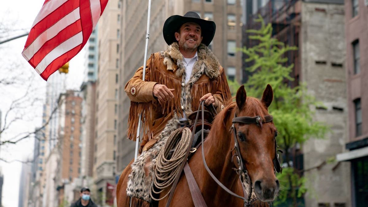Cowboys for Trump founder Couy Griffin rides down street on horse with American flag