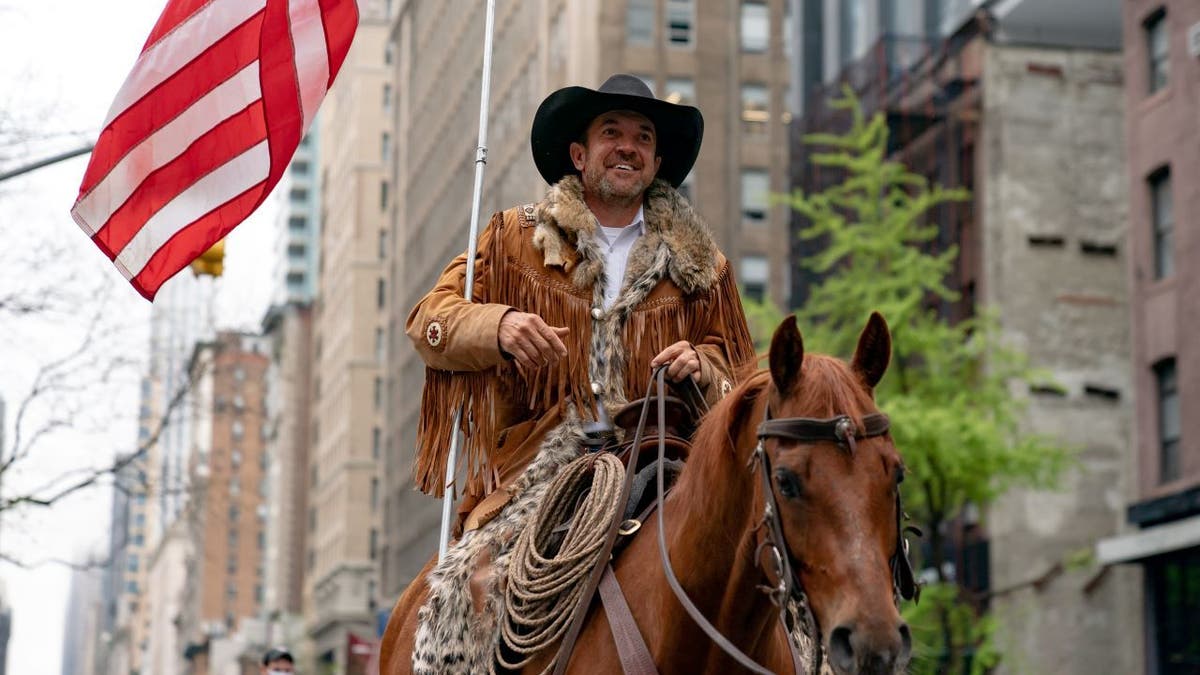 Cowboys for Trump founder Couy Griffin rides down street on horse with American flag