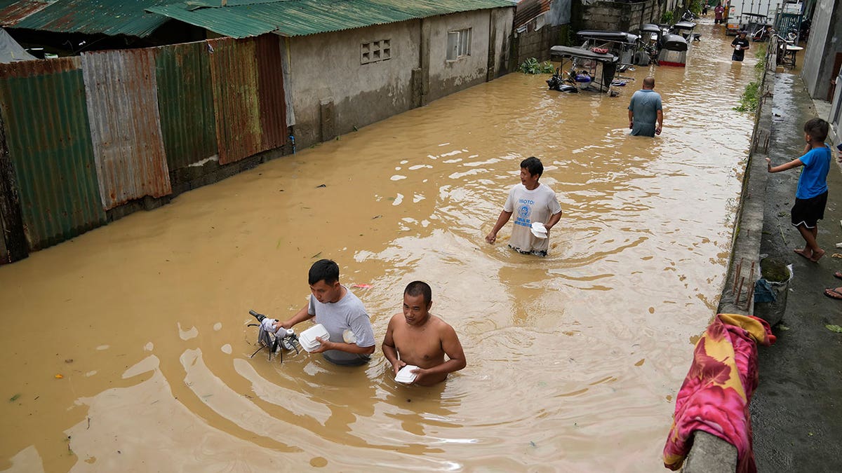 People wade through muddy water during typhoon flooding in the Phillipines