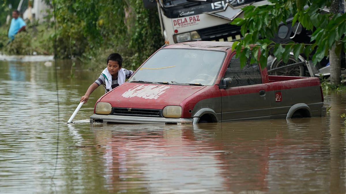 A man pullsa red minivan through muddy waters in the Phillipines