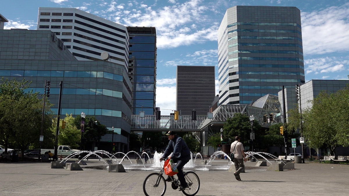 man rides bicycle past fountain in Portland