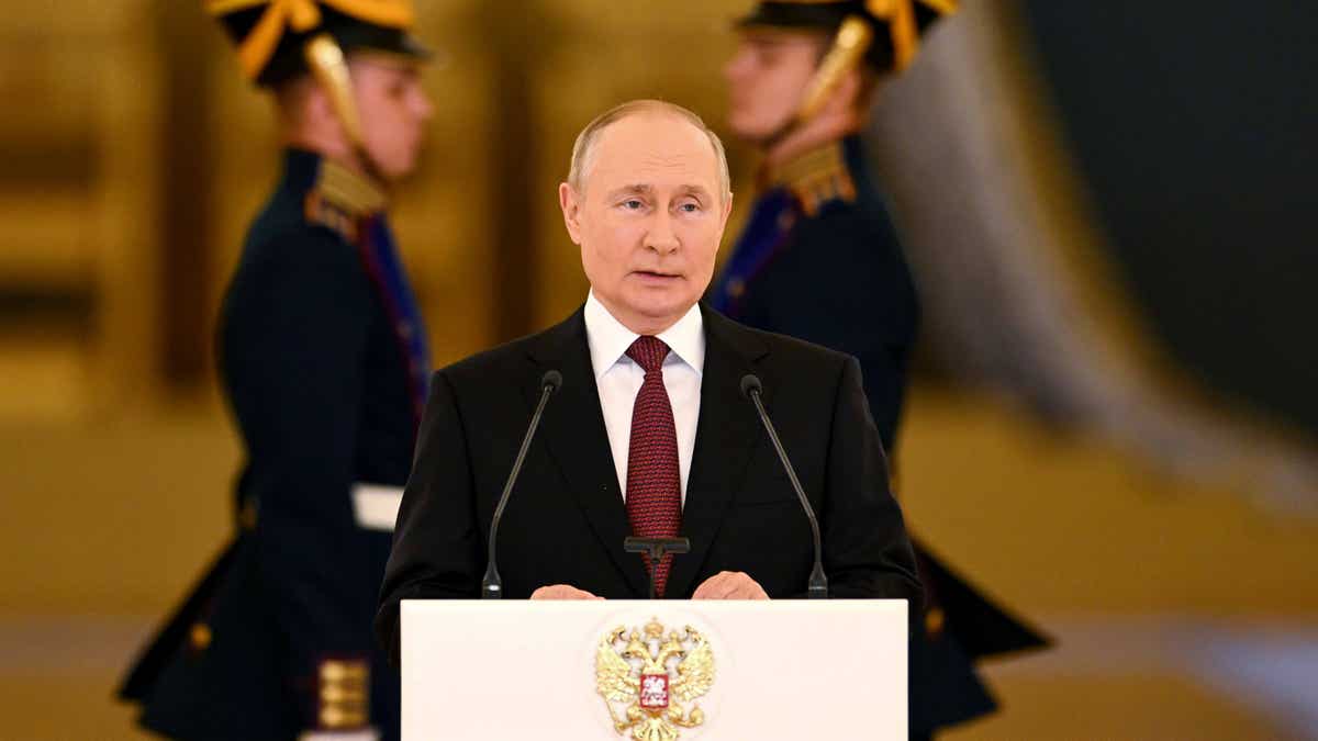 Vladimir Putin stands at a podium