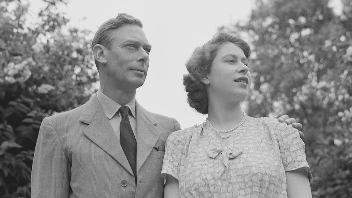 Black and white photo of young Queen Elizabeth and her father, the King, standing outside