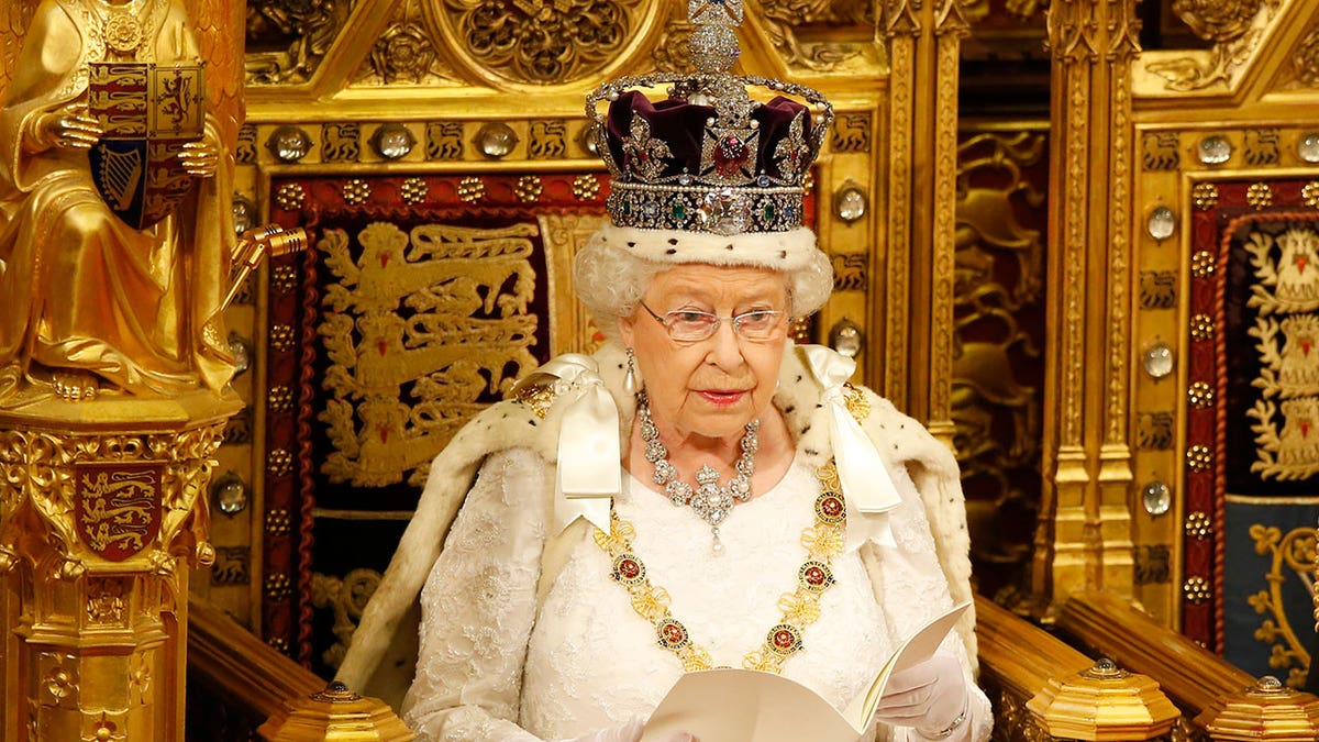 Queen Elizabeth II sits in her full regal ensemble.