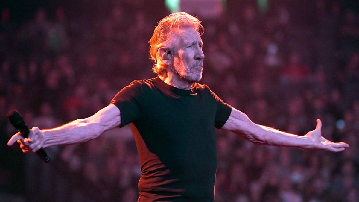Pink Floyd's Roger Waters with his arms out while holding a microphone