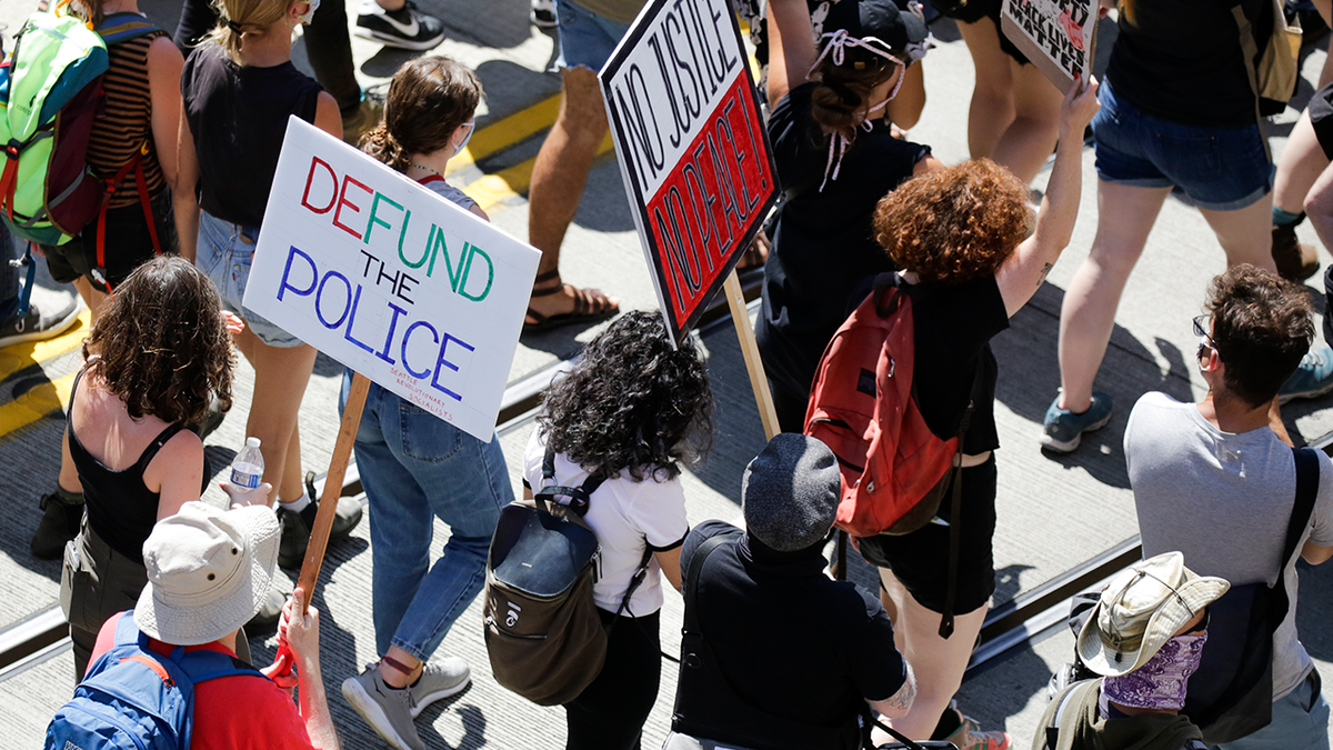 Photo shows protesters in Seattle holding defund the police signs during a demonstration in 2020